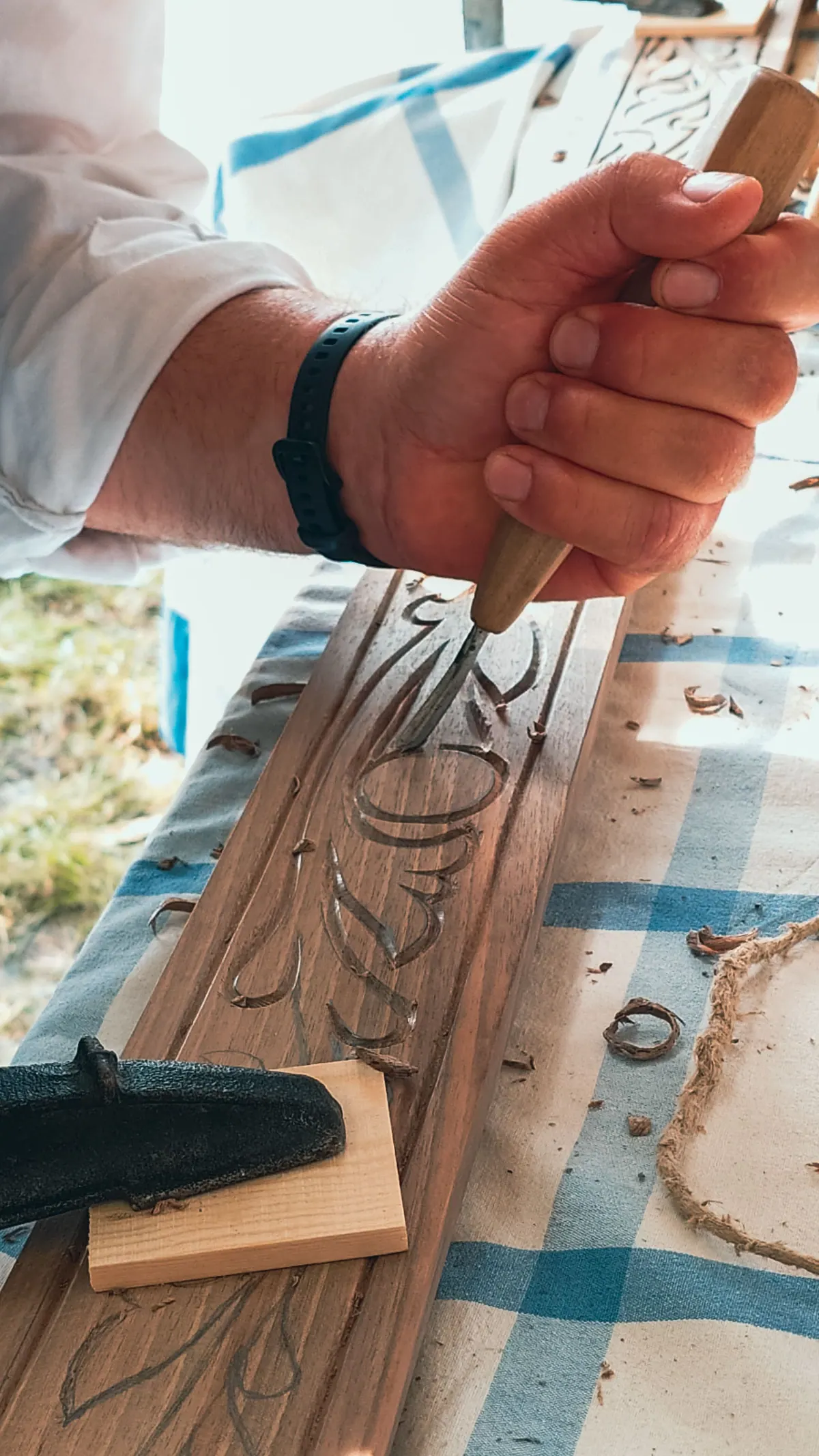 A hand carving letters into a board